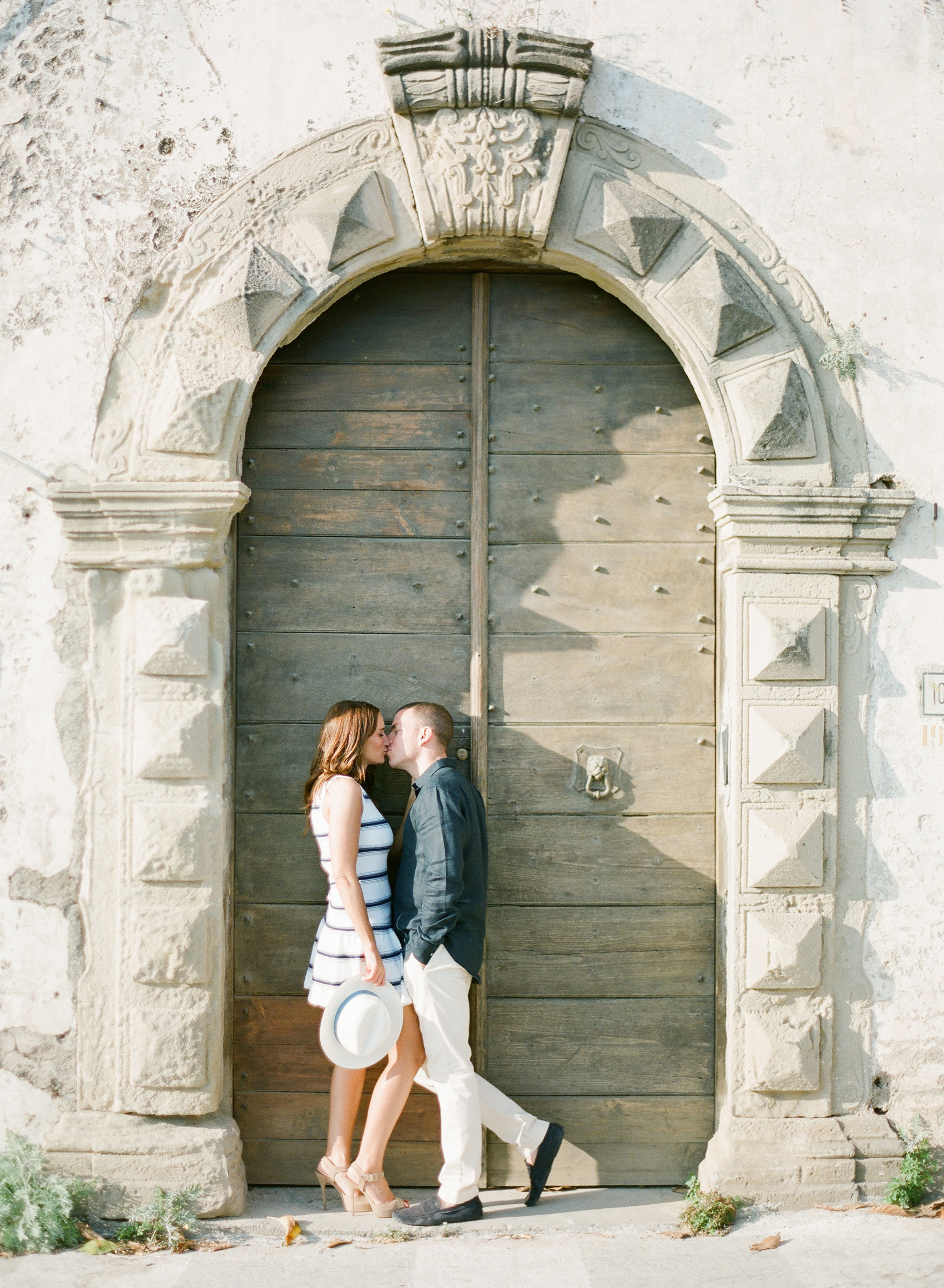 Andy and Adam kissing in front of a historical building in Italy