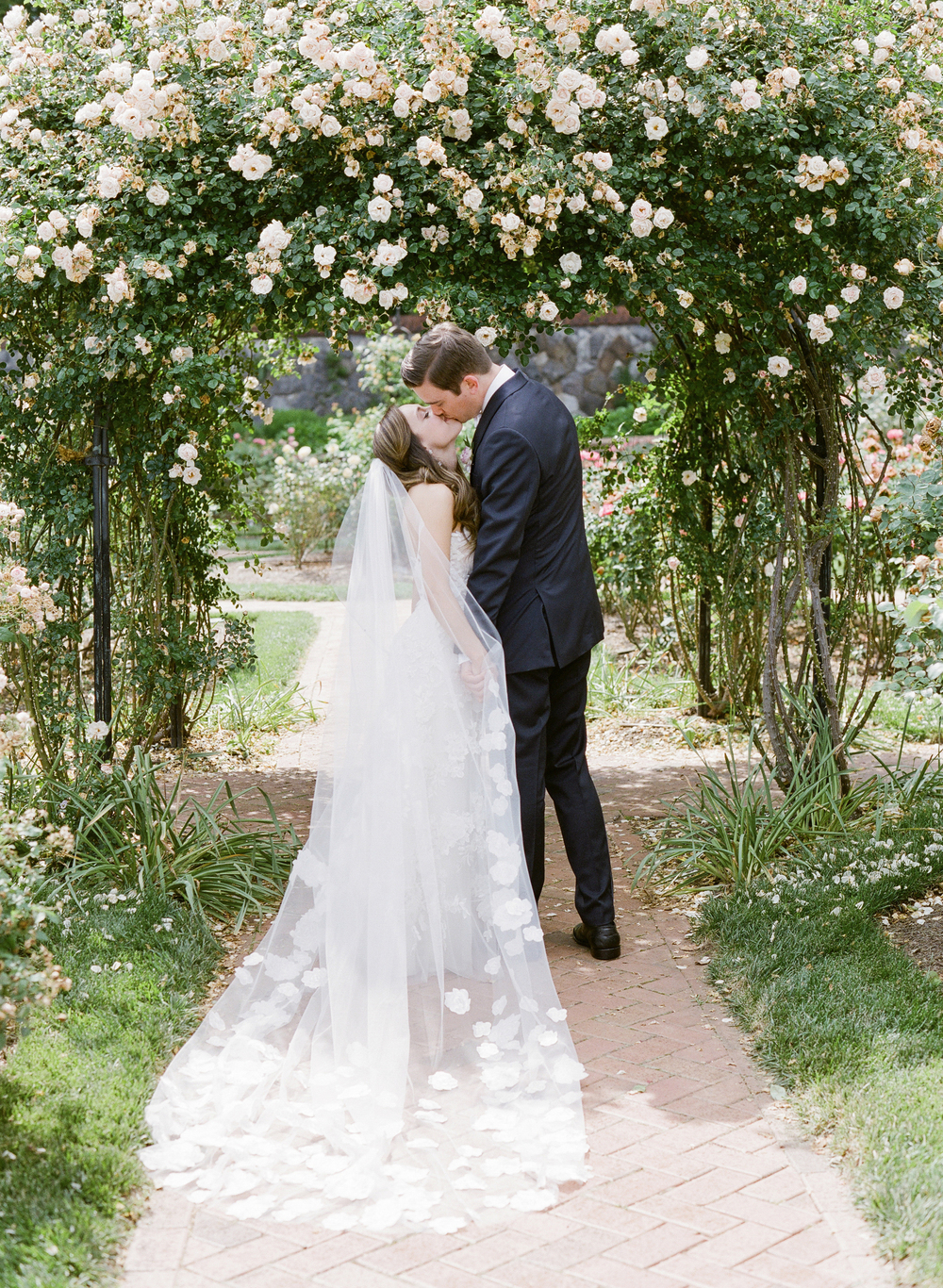 bride and groom kiss under floral arch at the Biltmore Estate in Asheville