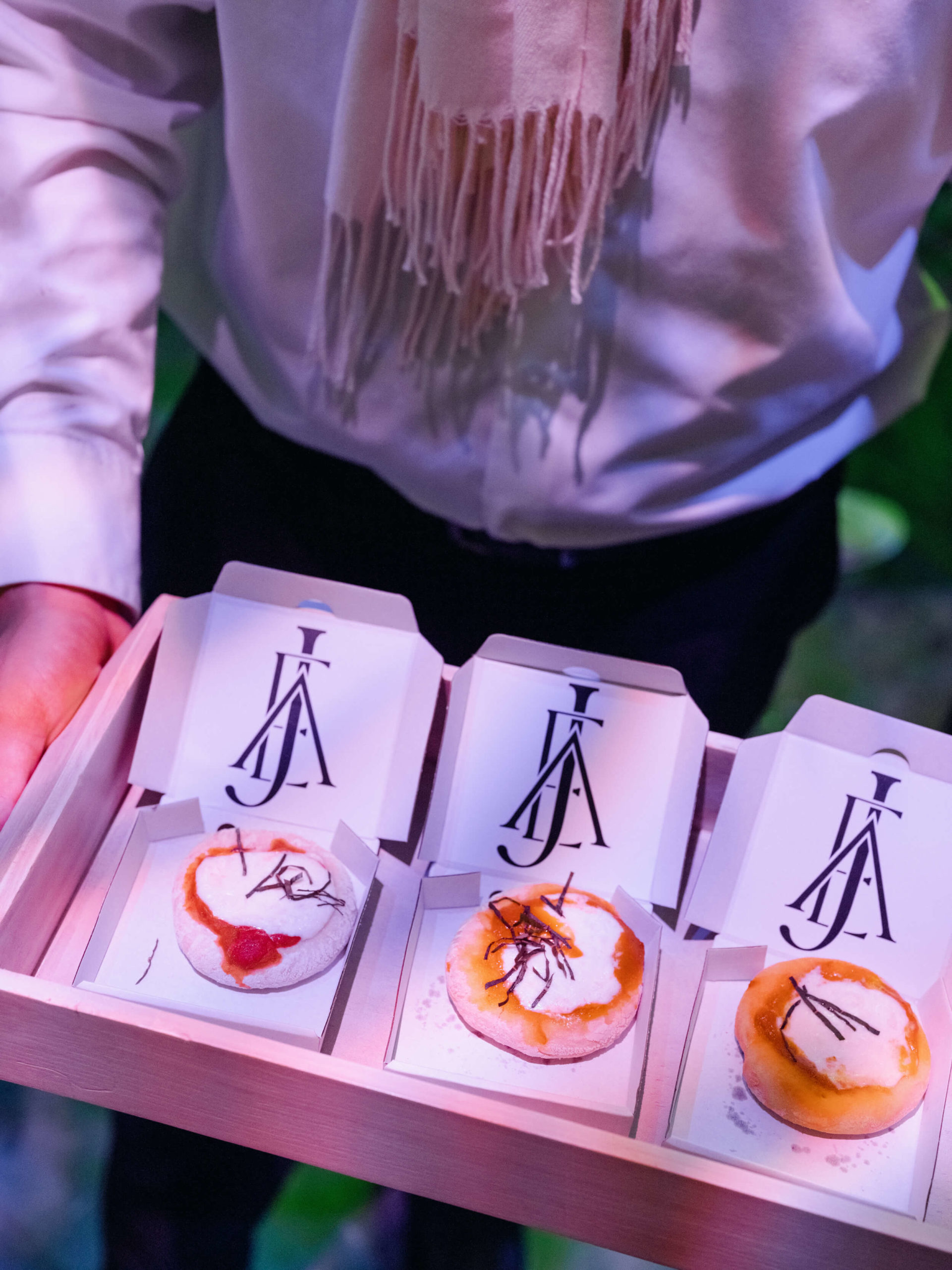 mini pizzas served in monogrammed boxes on a tray 