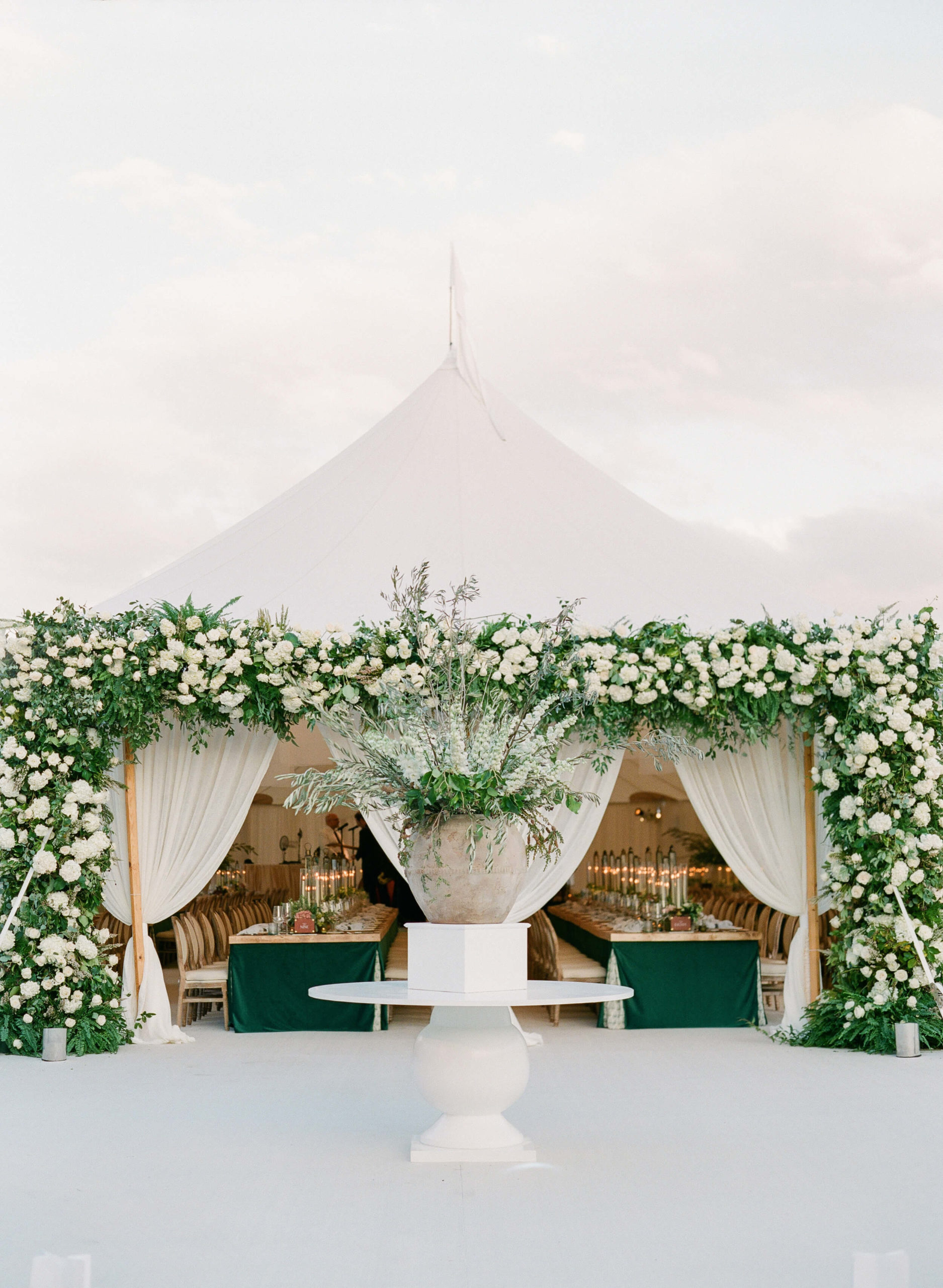 a white floral archway at the entrance to tent