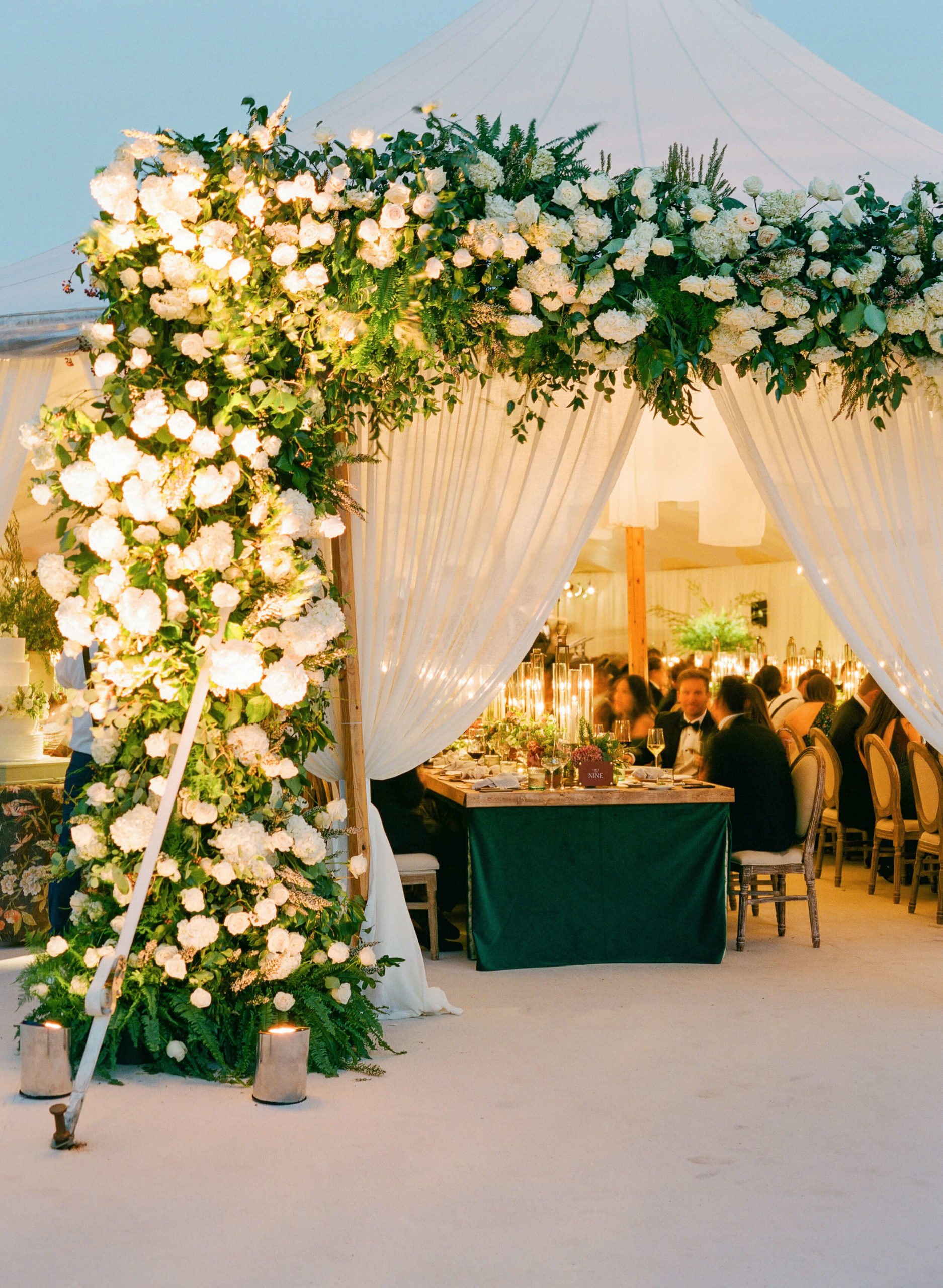 white floral archway at opening of dinner tent