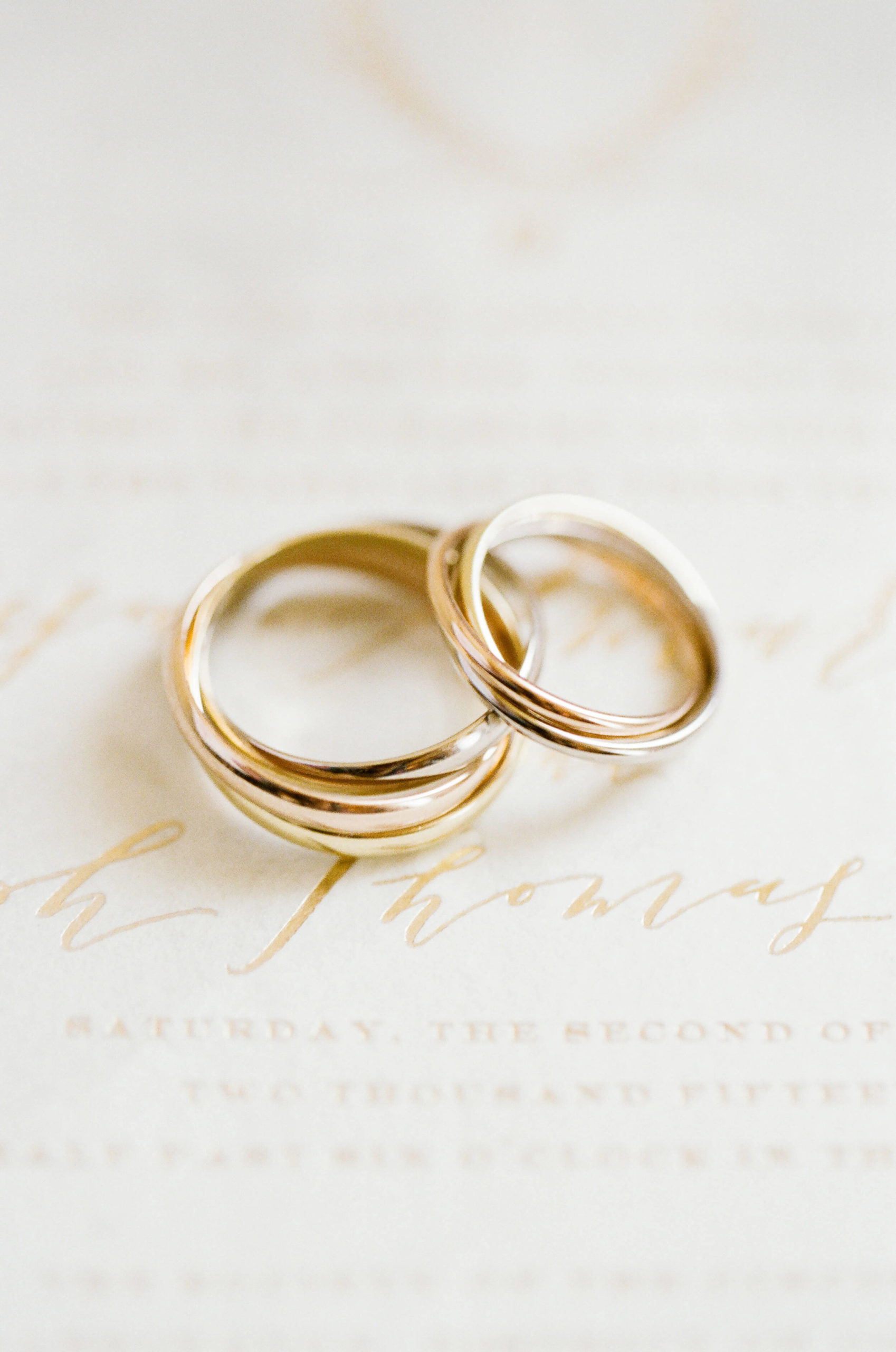 gold wedding bands on top of wedding invitation