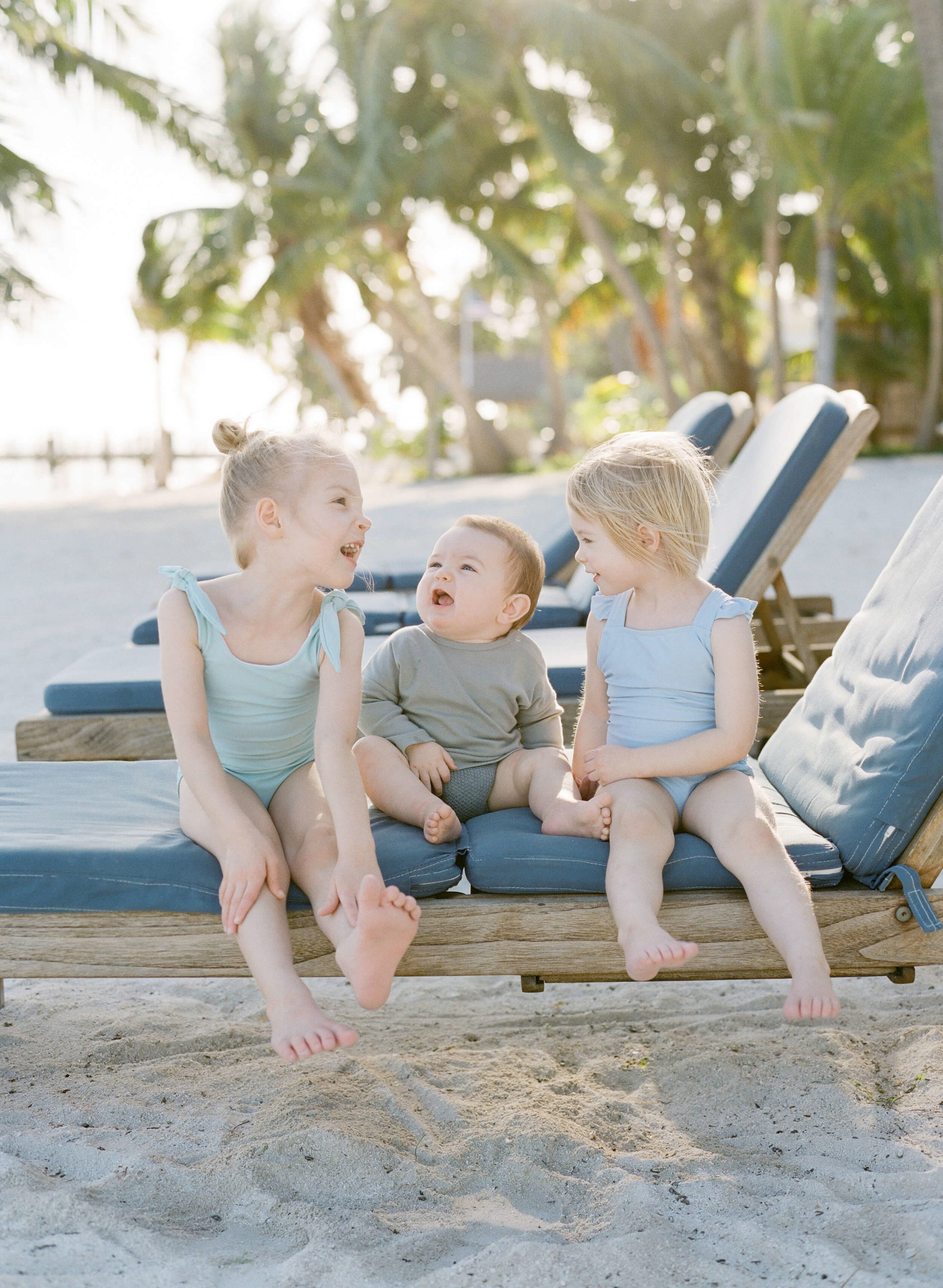 three children on a chaise lounge on the beach