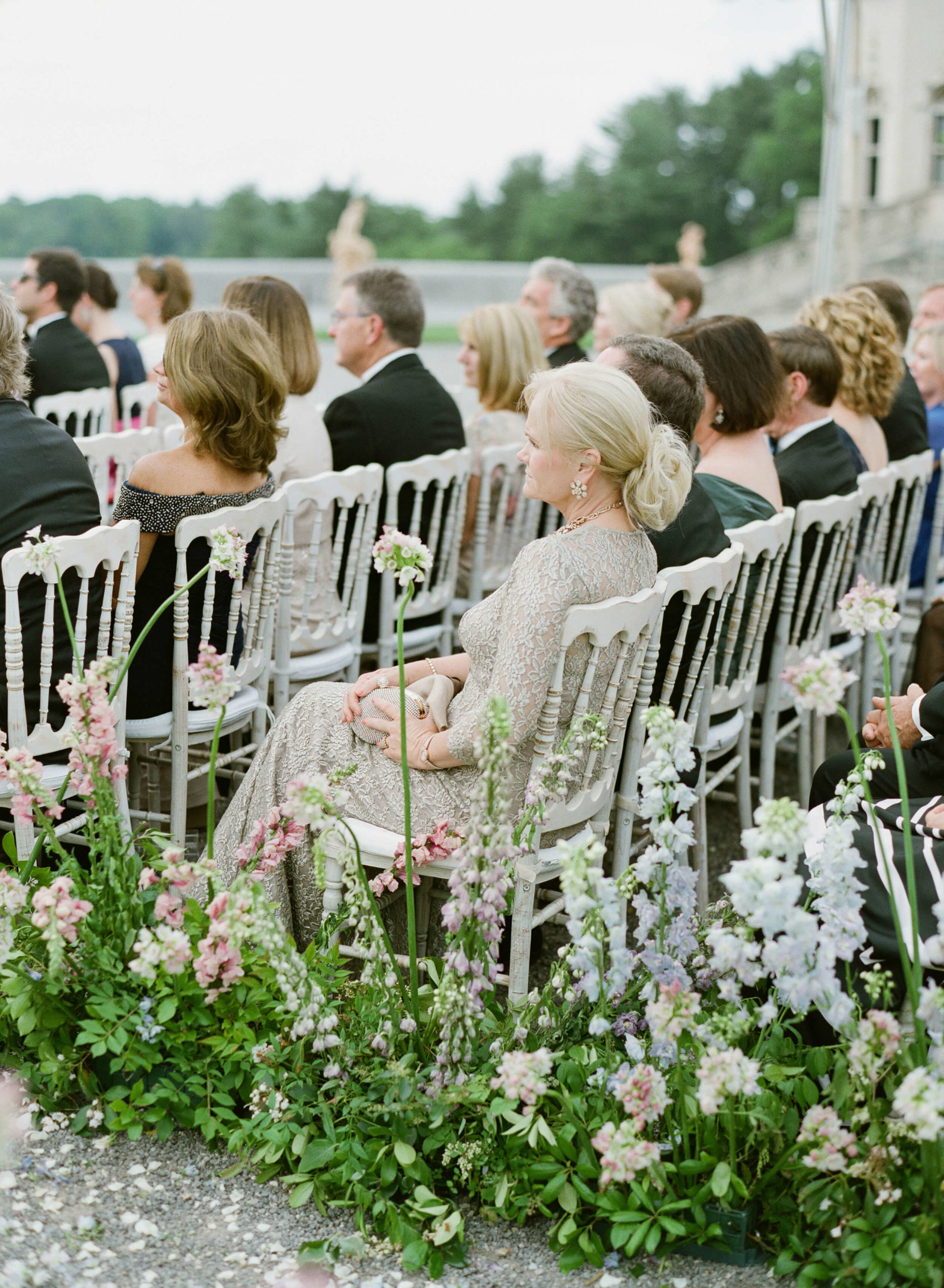 guests in white wooden chairs at outdoor garden wedding ceremony