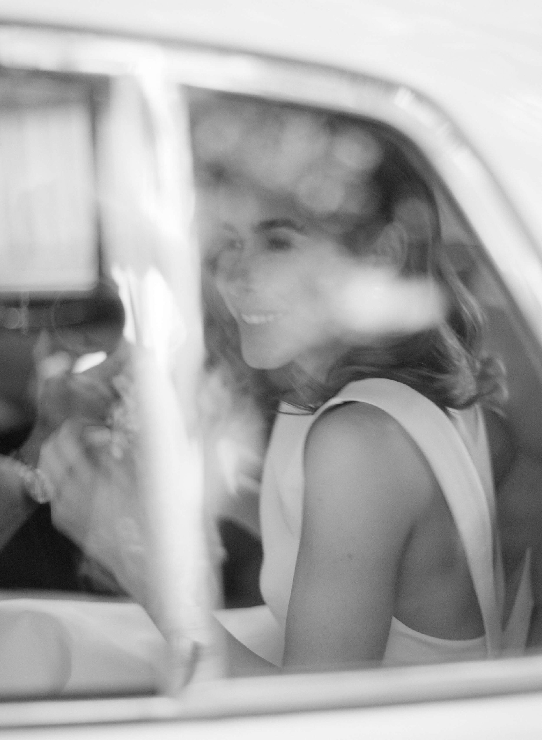 Bride smiling in the getaway car 