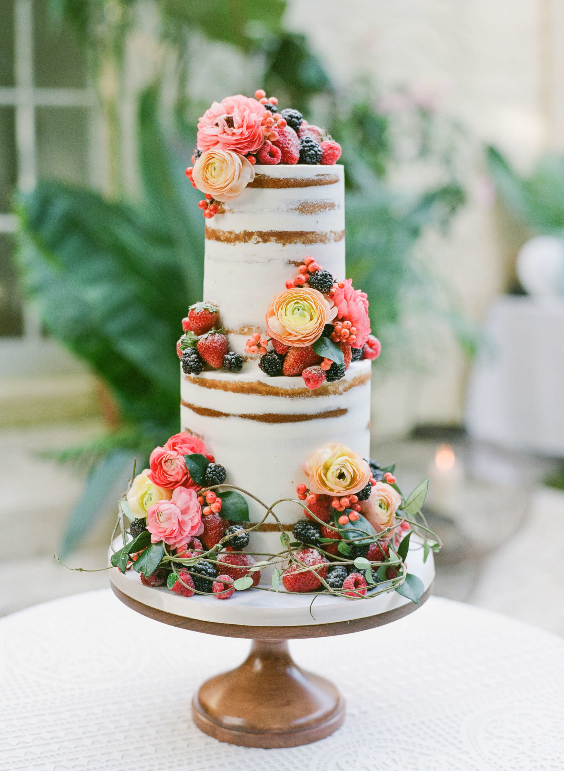 Colorful wedding cake covered in fruit and flowers.