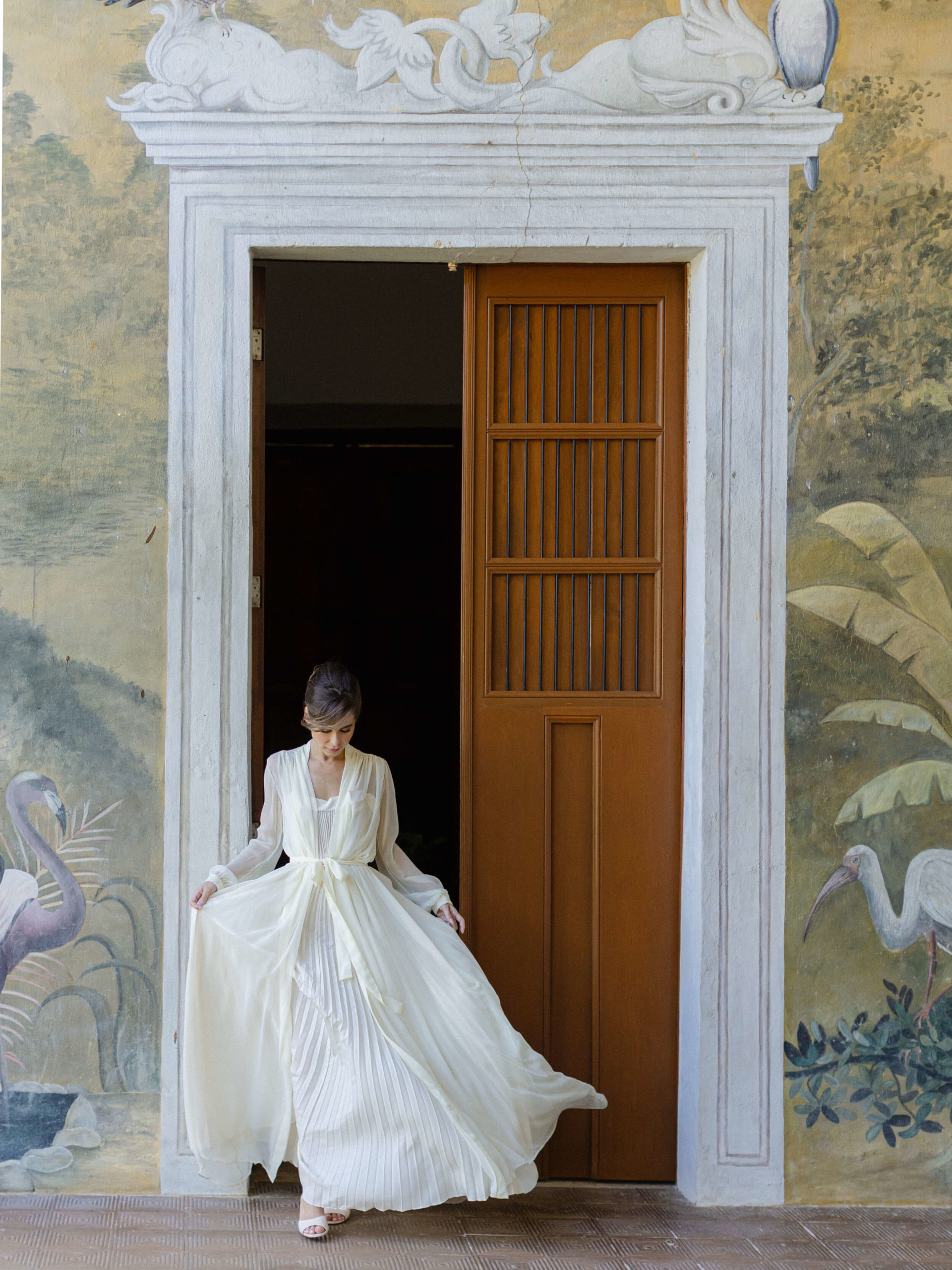 Bride walks through ornate door in dressing gown