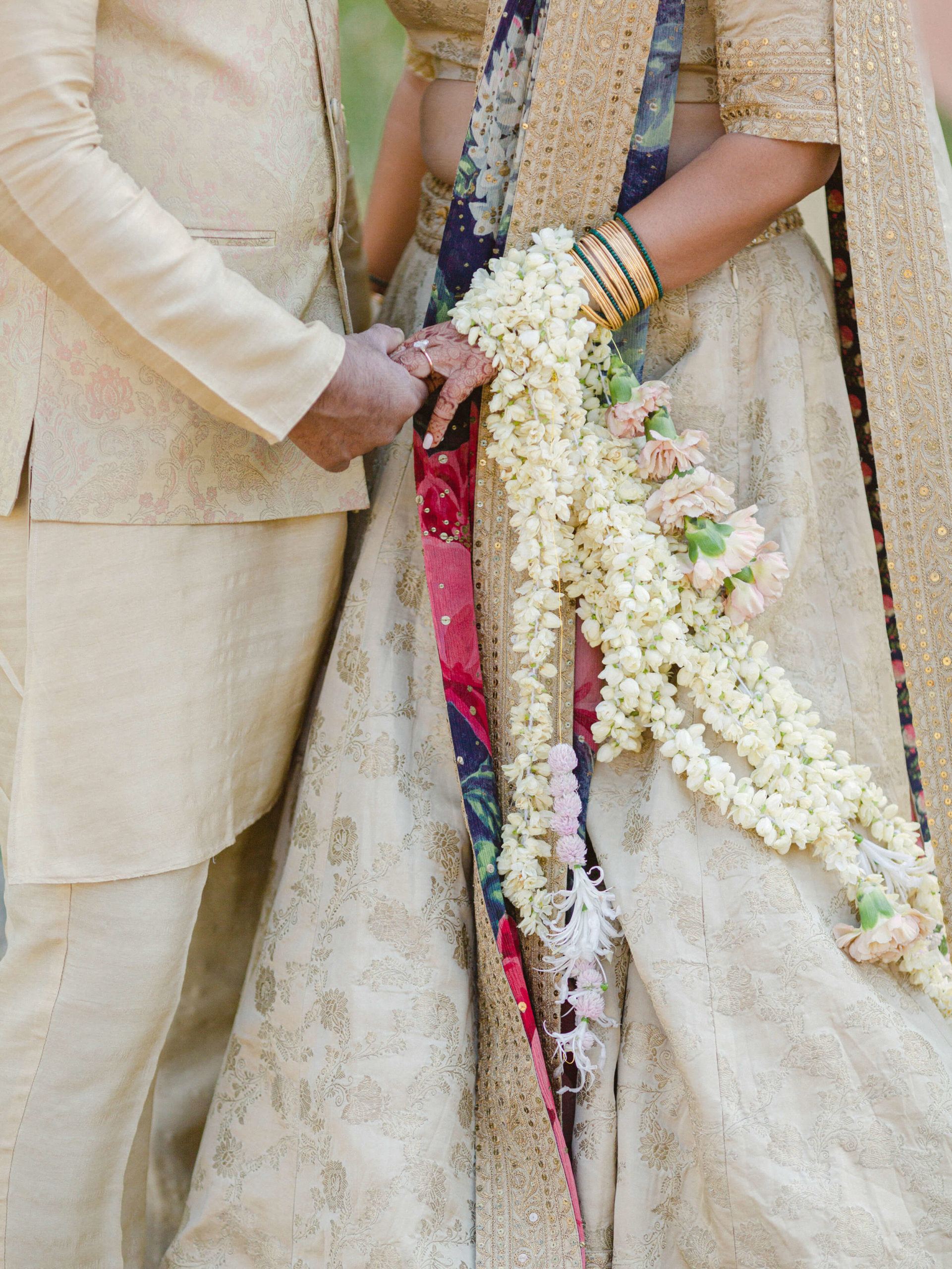 Sapna and Ari holding hands in their Indian wedding atire