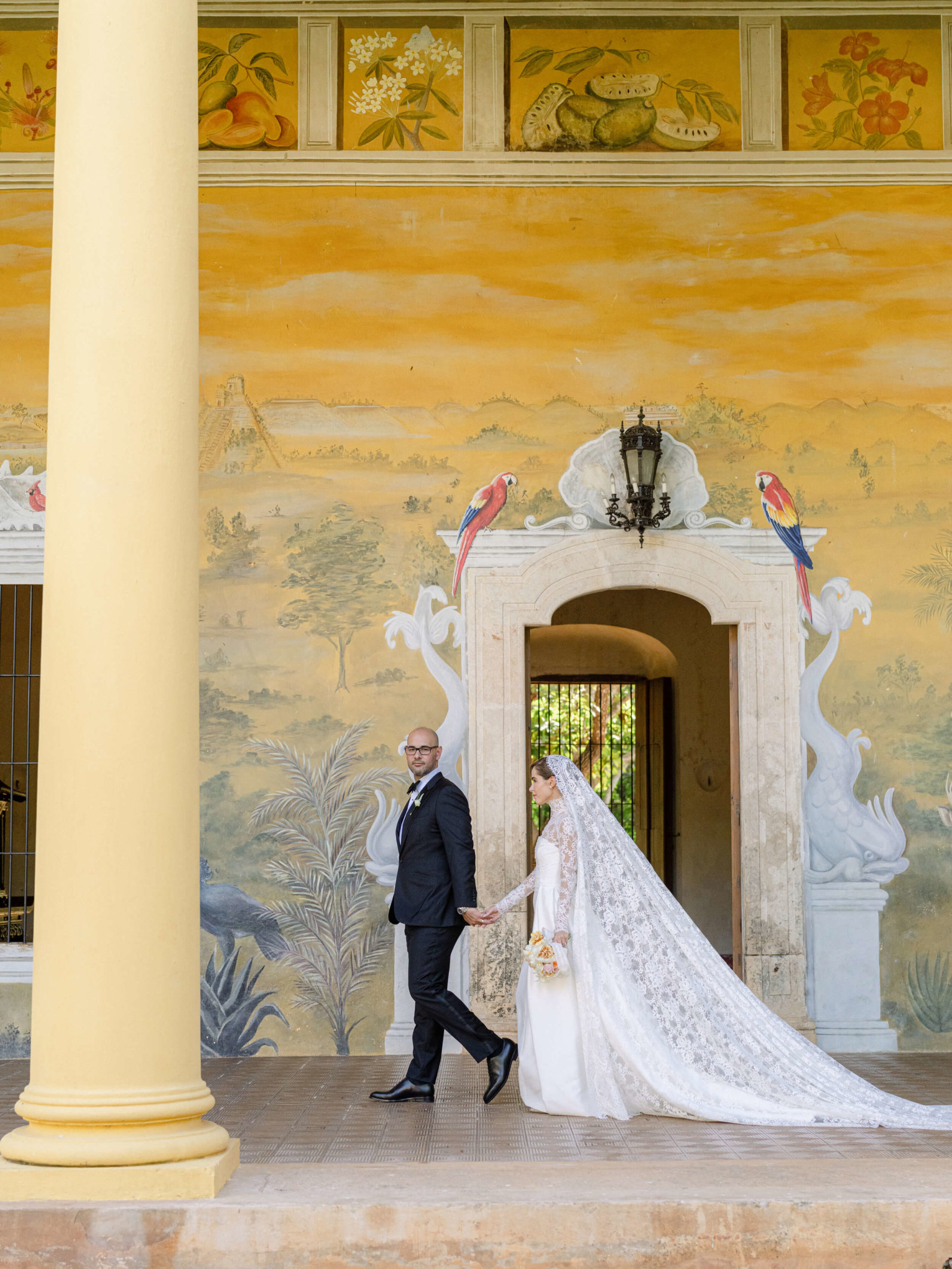 Bride and groom walking in front of elaborate mural