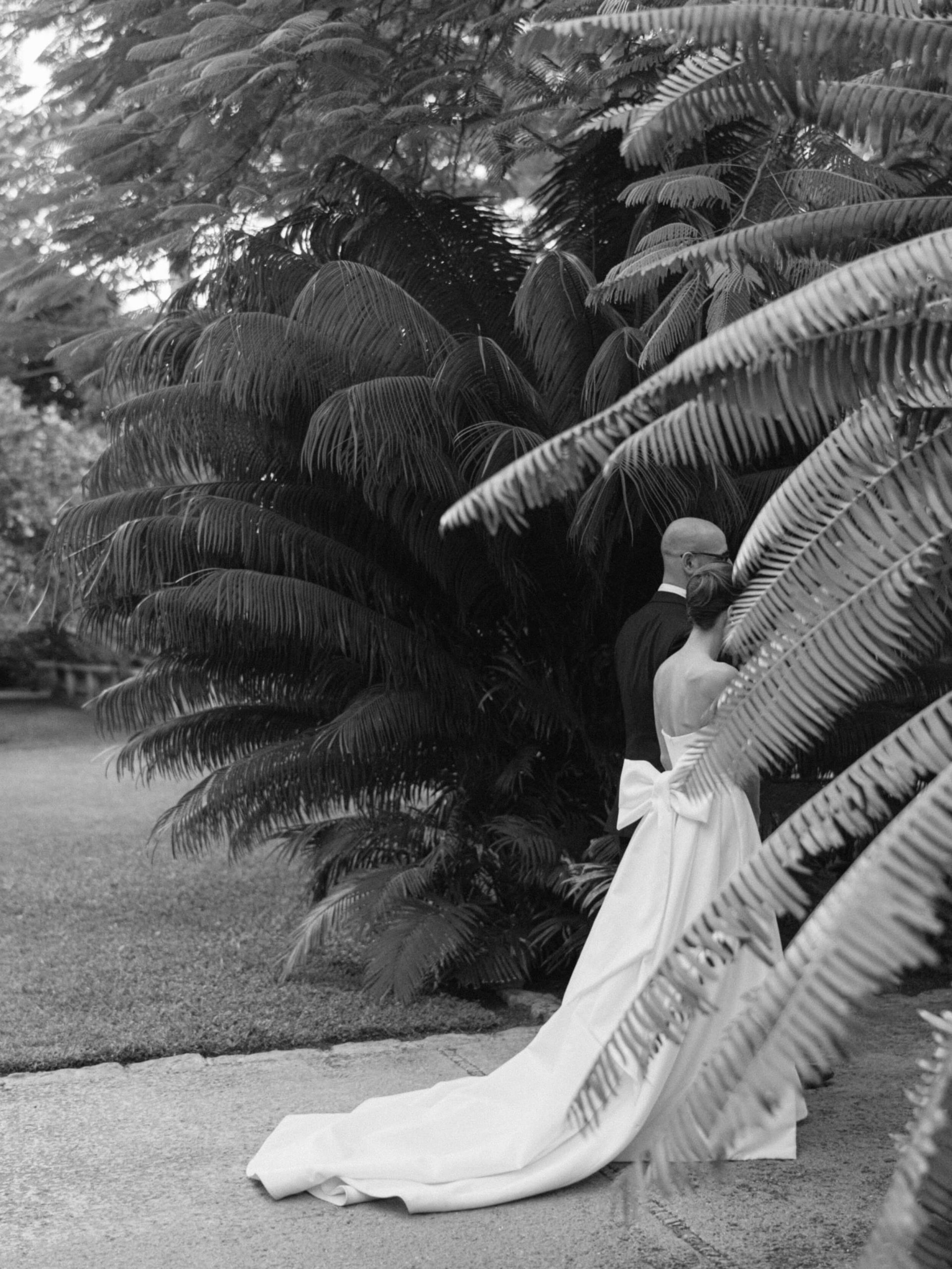 bride and groom walking along a path surrounded by trees