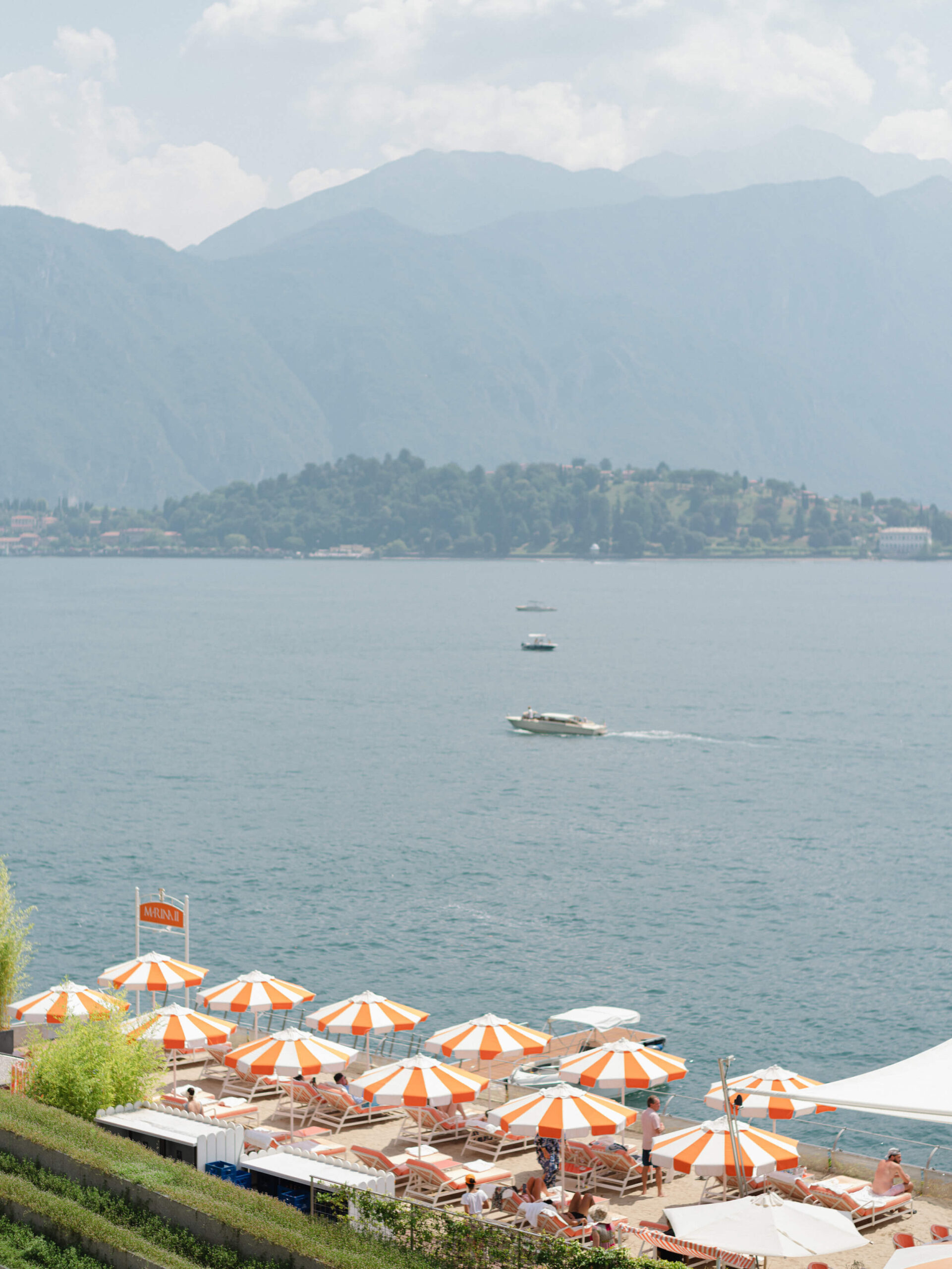 Umbrellas on the shores of Lake Como, boats in the distance