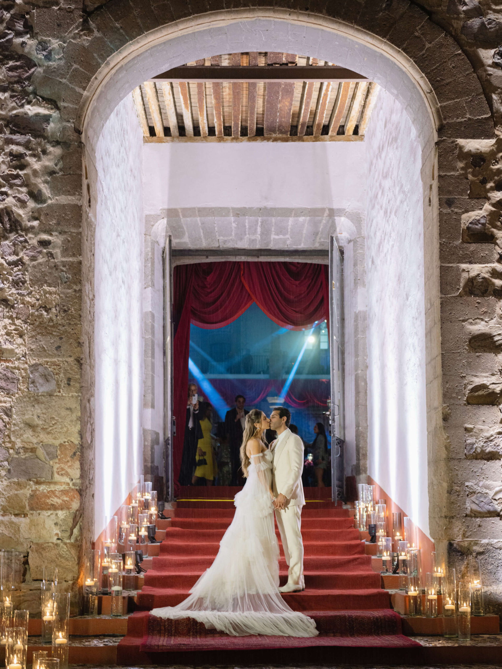 Ashley and Brian kissing in the stone archway of the entrance to their welcome party