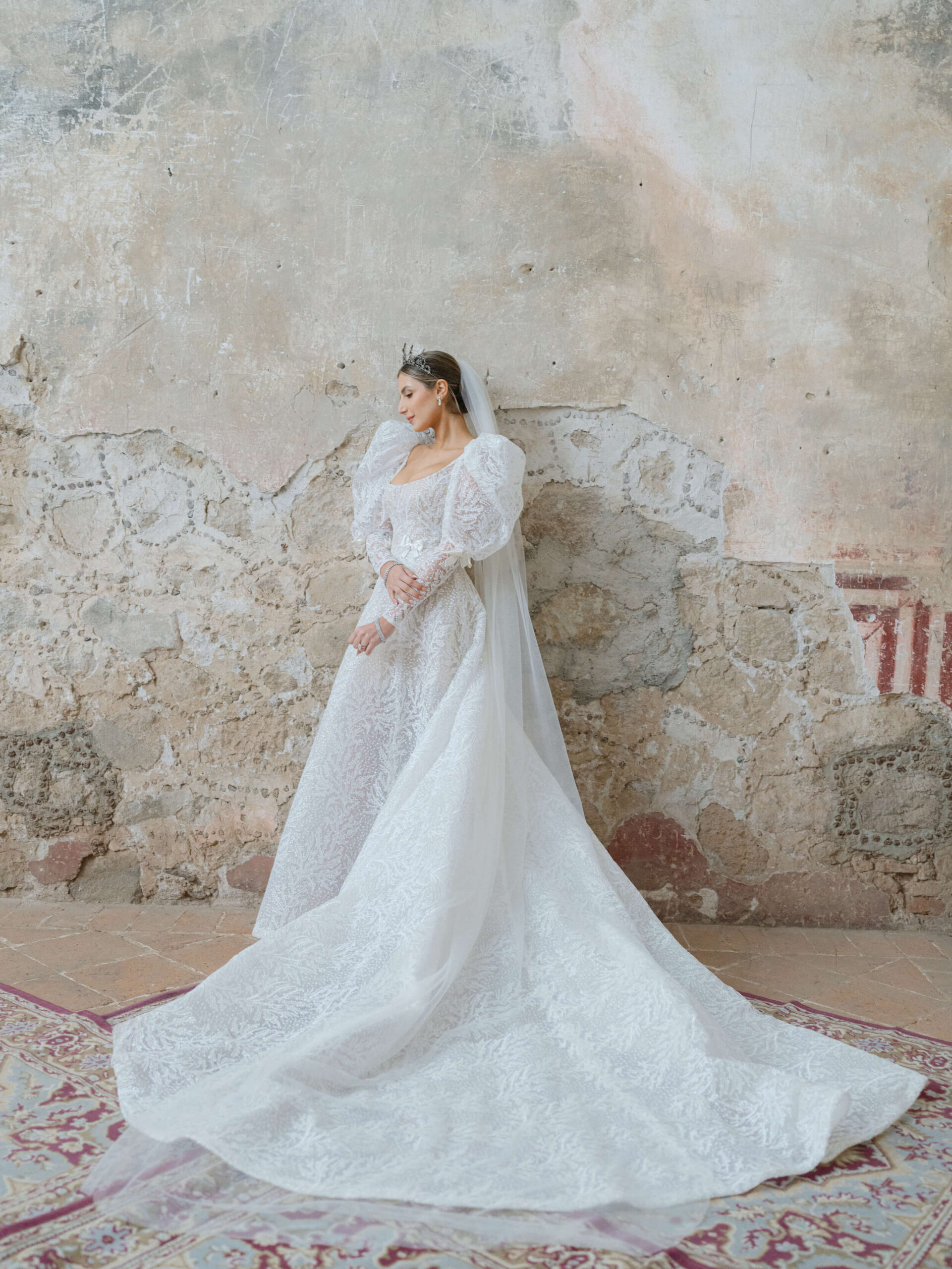 Ashley posing in her Reem Acra wedding gown in a room with crumbling walls and oriental rugs