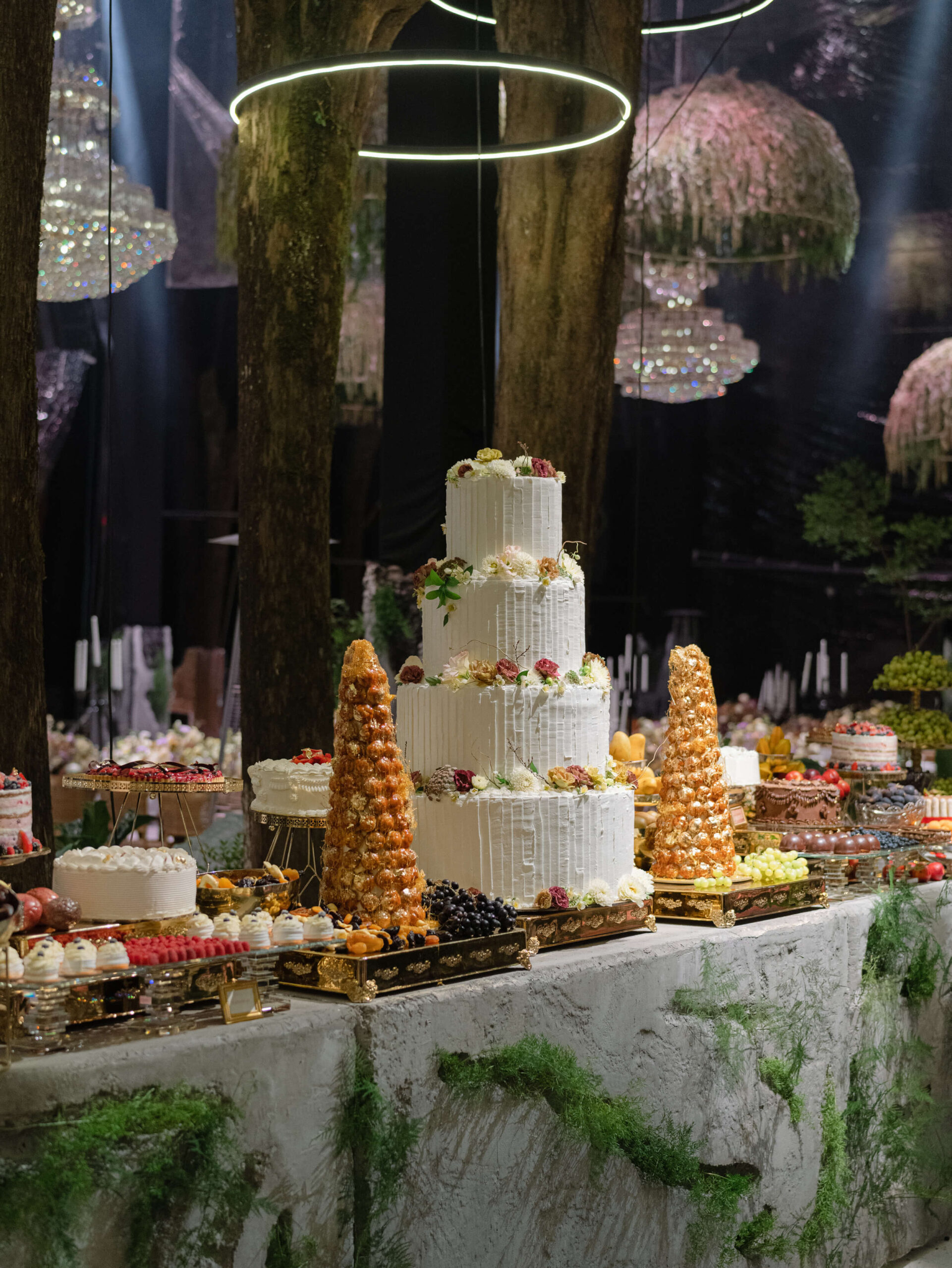 Cake and deserts lined on stone slab tables covered in moss
