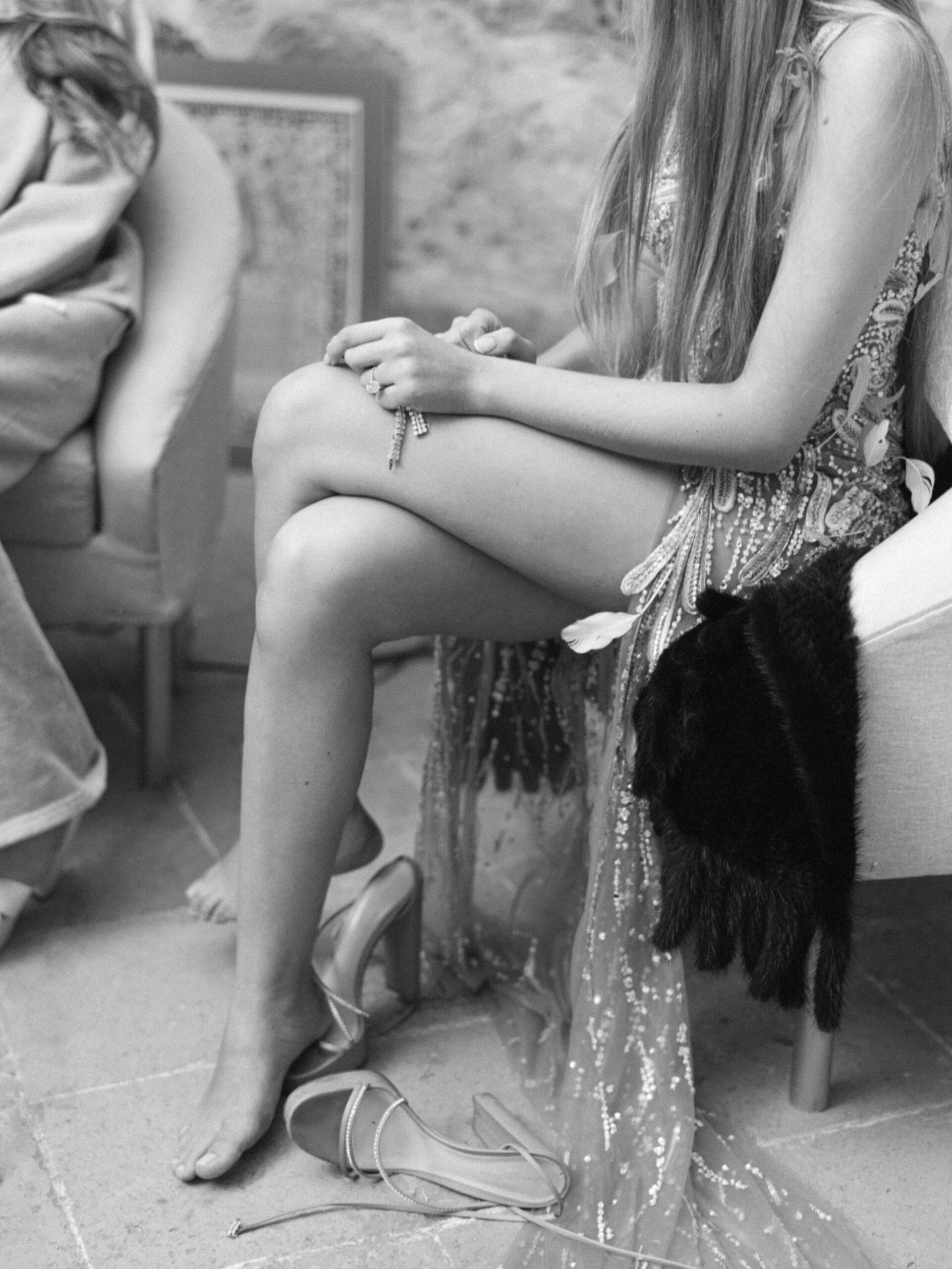 A wedding guest lounges with her shoes off