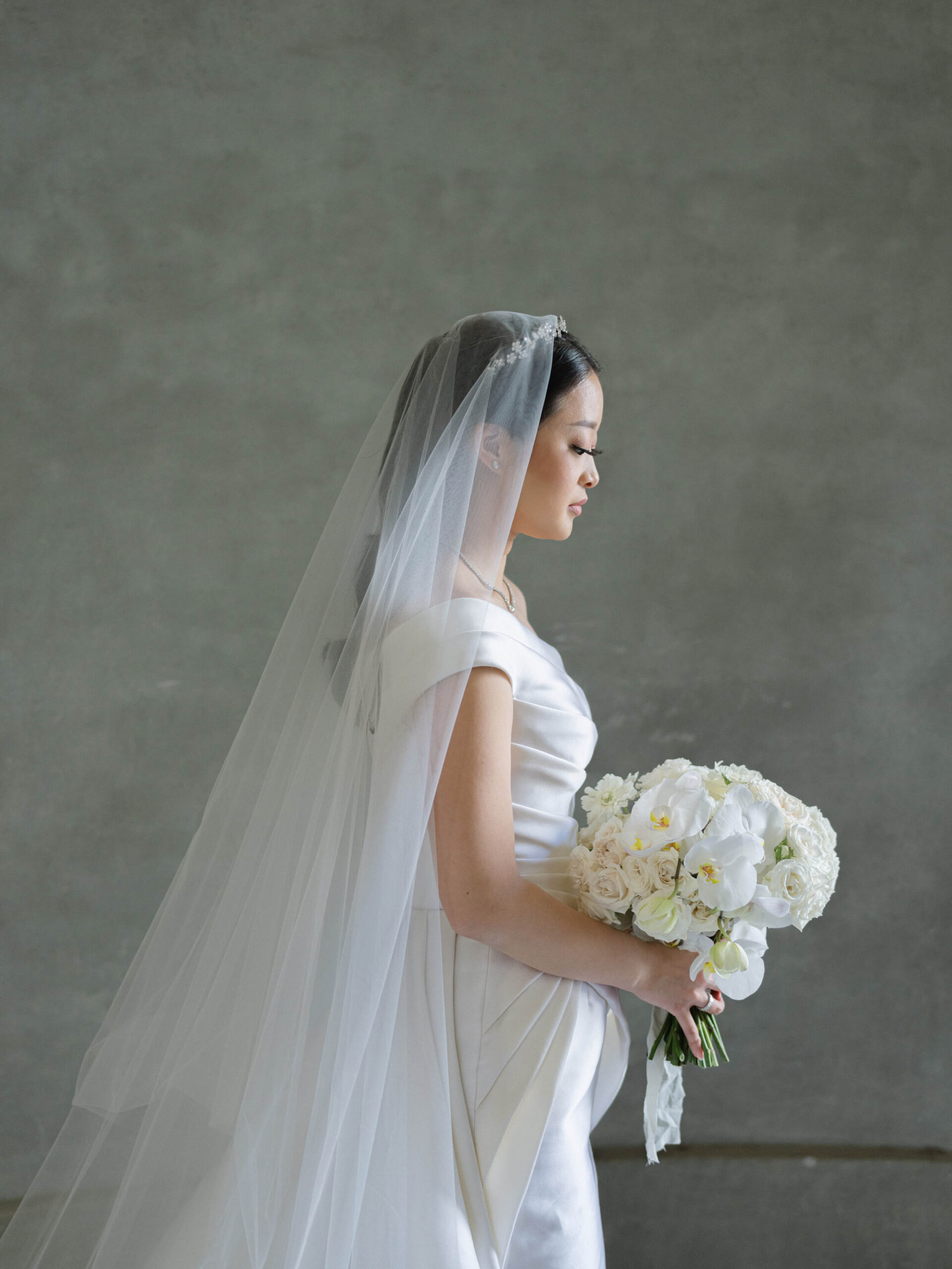 Side profile of bride in her gown, holding her bouquet