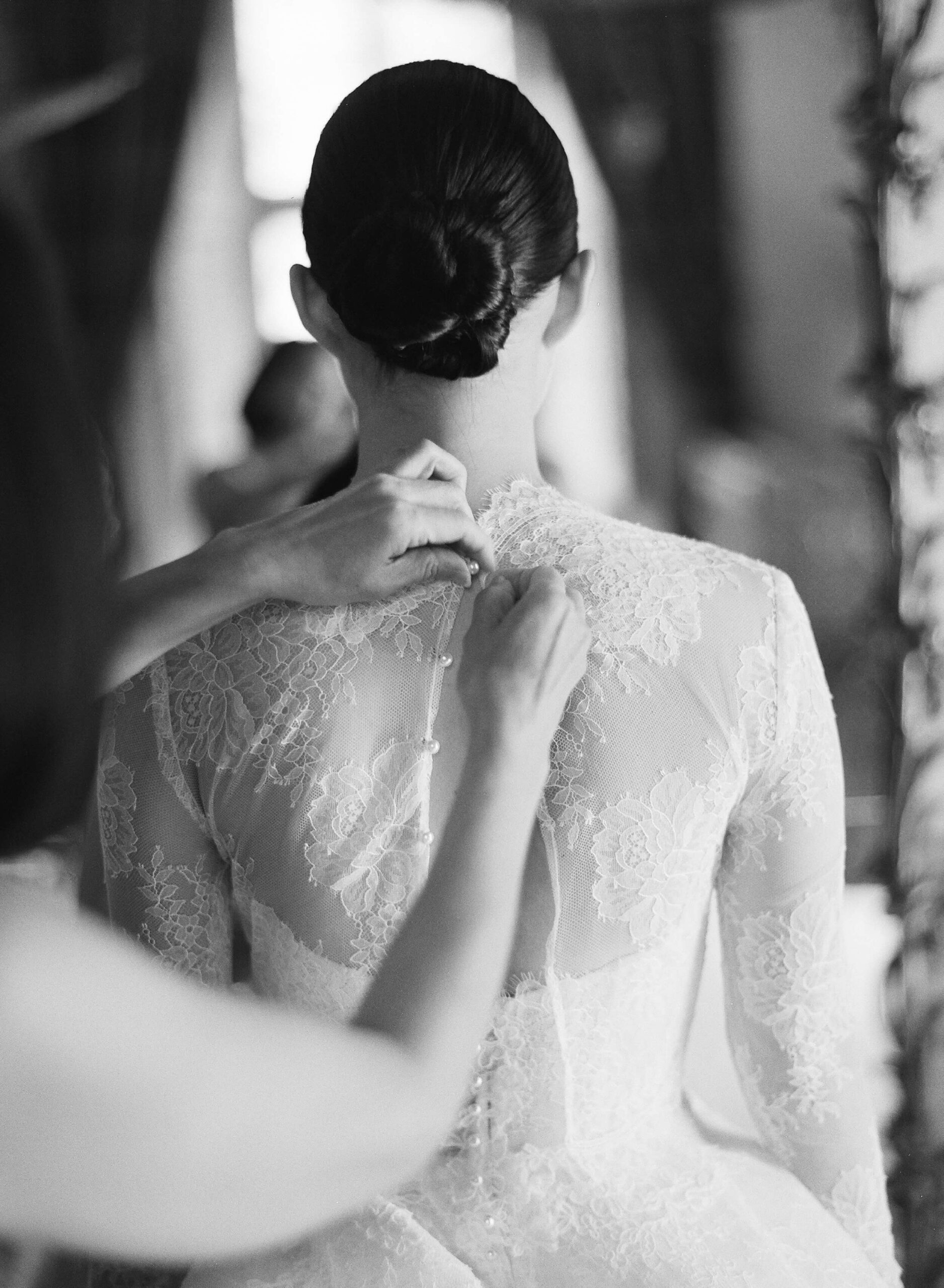 family member carefully buttons the elegantly laced wedding gown
